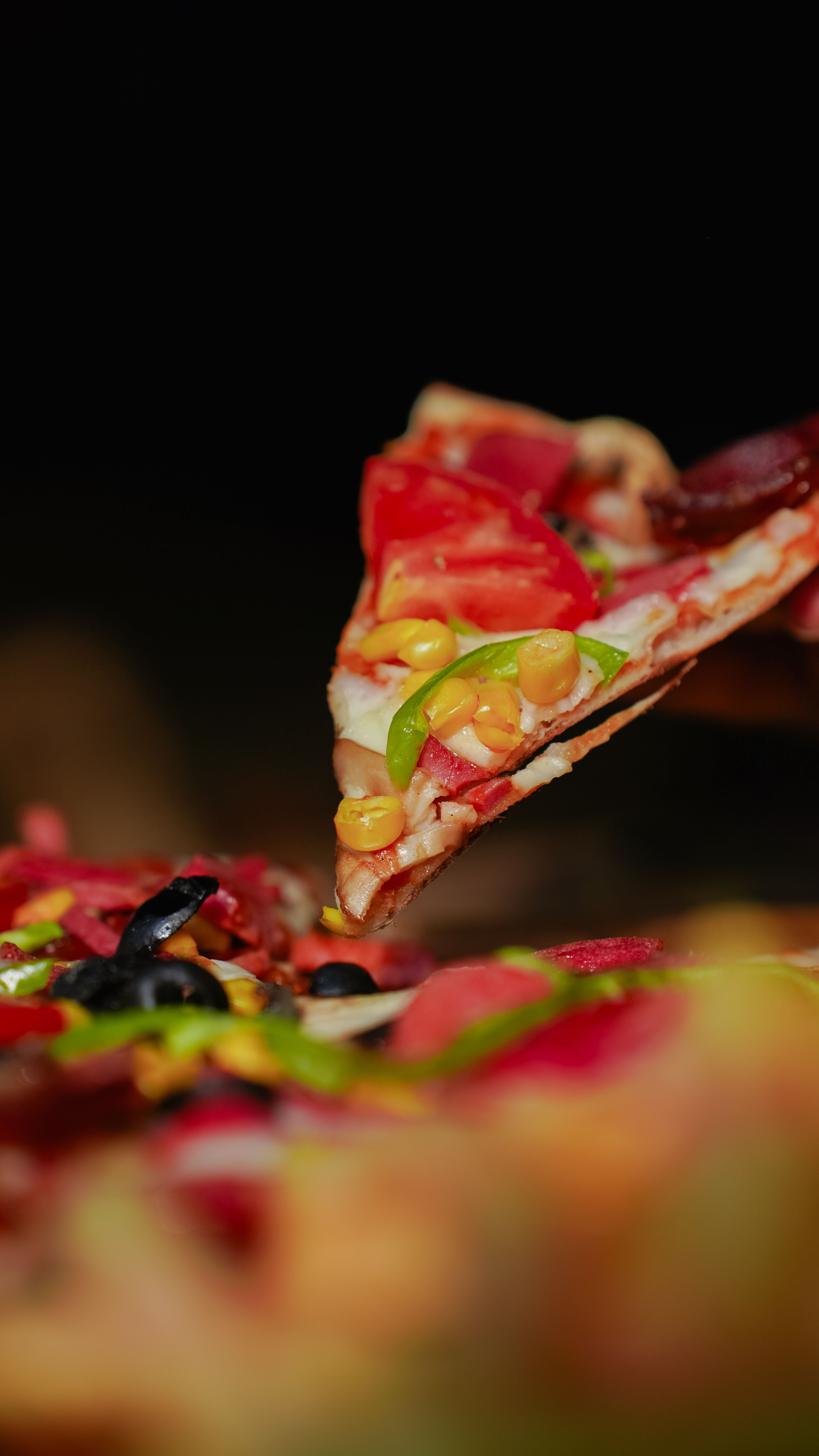 Close-up of a vegetable pizza slice with vibrant toppings, ready to serve.