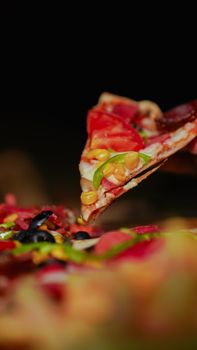 Close-up of a vegetable pizza slice with vibrant toppings, ready to serve.
