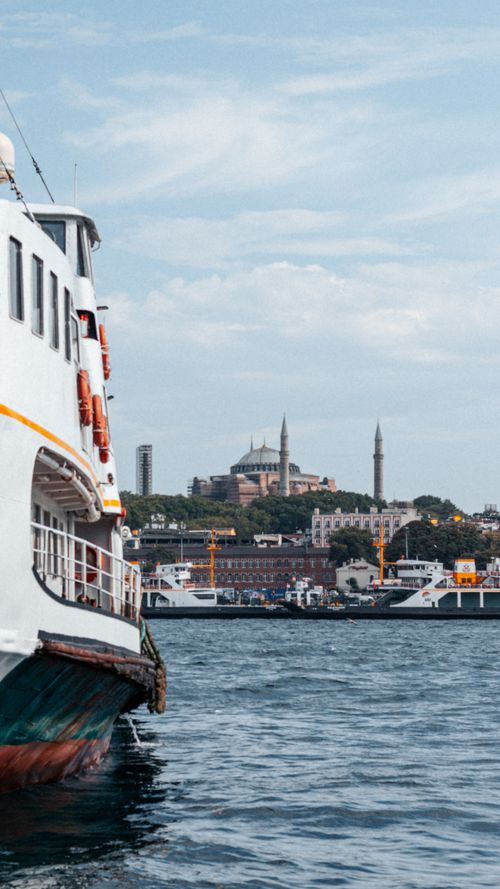 Free Ferry on a river with the Hagia Sophia in the background under a clear blue sky, showcasing Istanbul's iconic skyline. Stock Photo