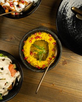 Top view of a Middle Eastern dish garnished with pomegranates and herbs, served in a rustic bowl on a wooden table.