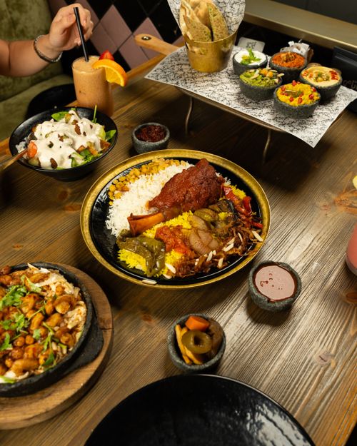 Free A vibrant Middle Eastern feast featuring rice, meat, and various appetizers on a wooden table. Stock Photo