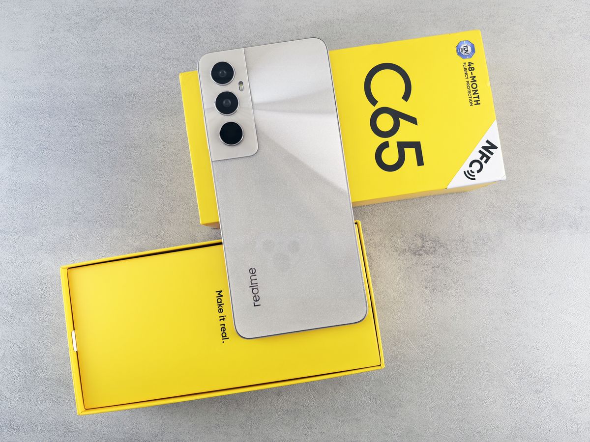 Smartphone apoiado sobre uma caixa amarela, representando uma foto secundária de produto em contexto