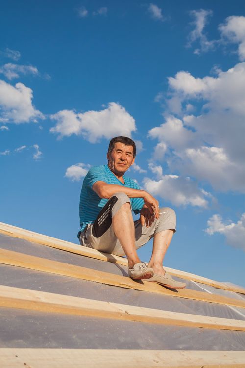 Free A man relaxes on a rooftop under a clear blue sky, enjoying a sunny day. Stock Photo