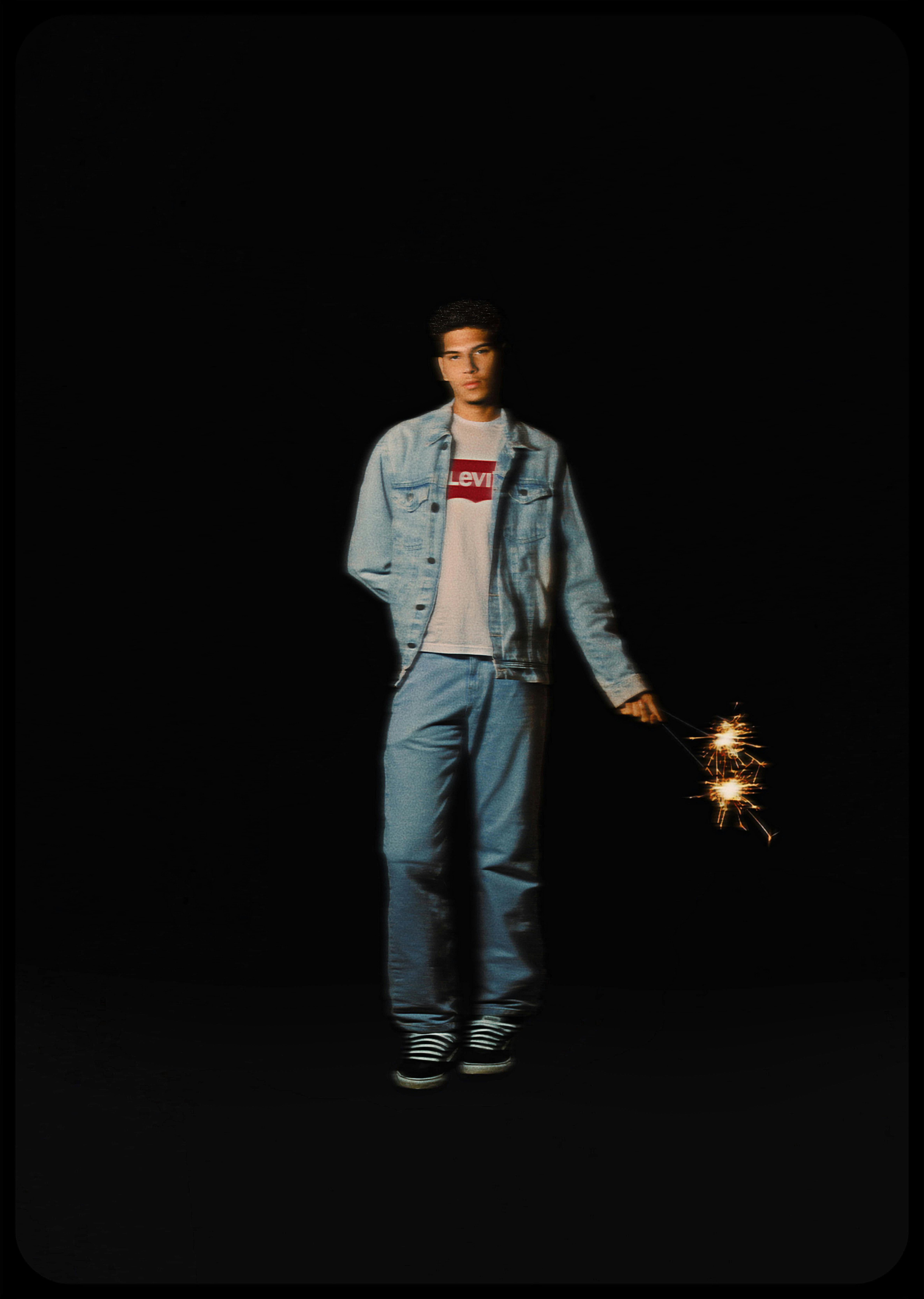 a man in jeans and jacket holding a sparkler