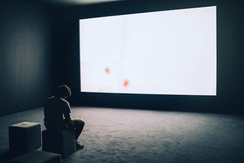 Free Man Sitting in Front of Turned-on Screen Stock Photo