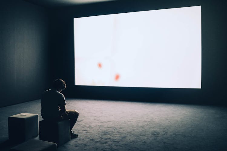 Man Sitting In Front Of Turned-on Screen