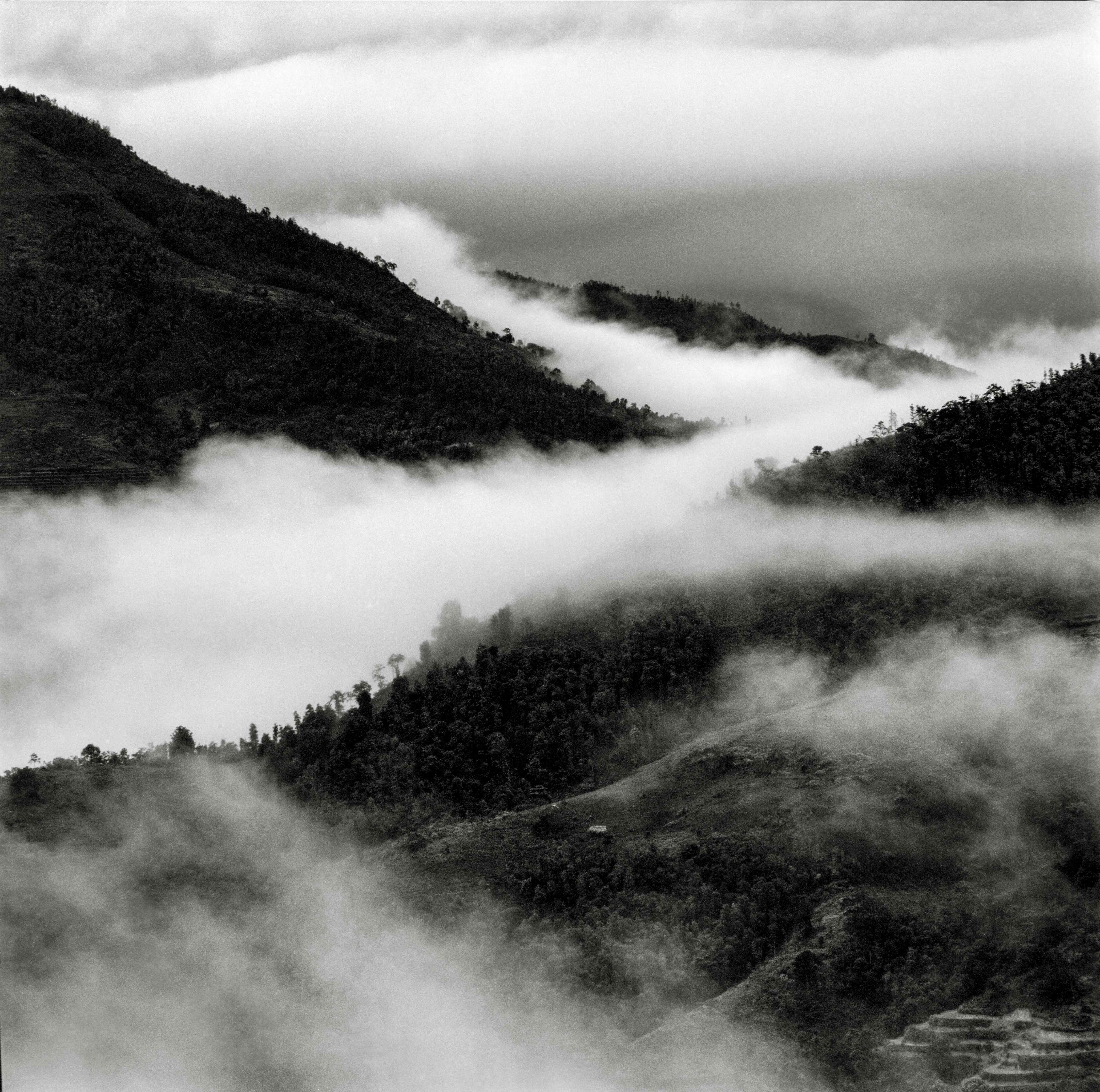 black and white photograph of mountains covered in fog