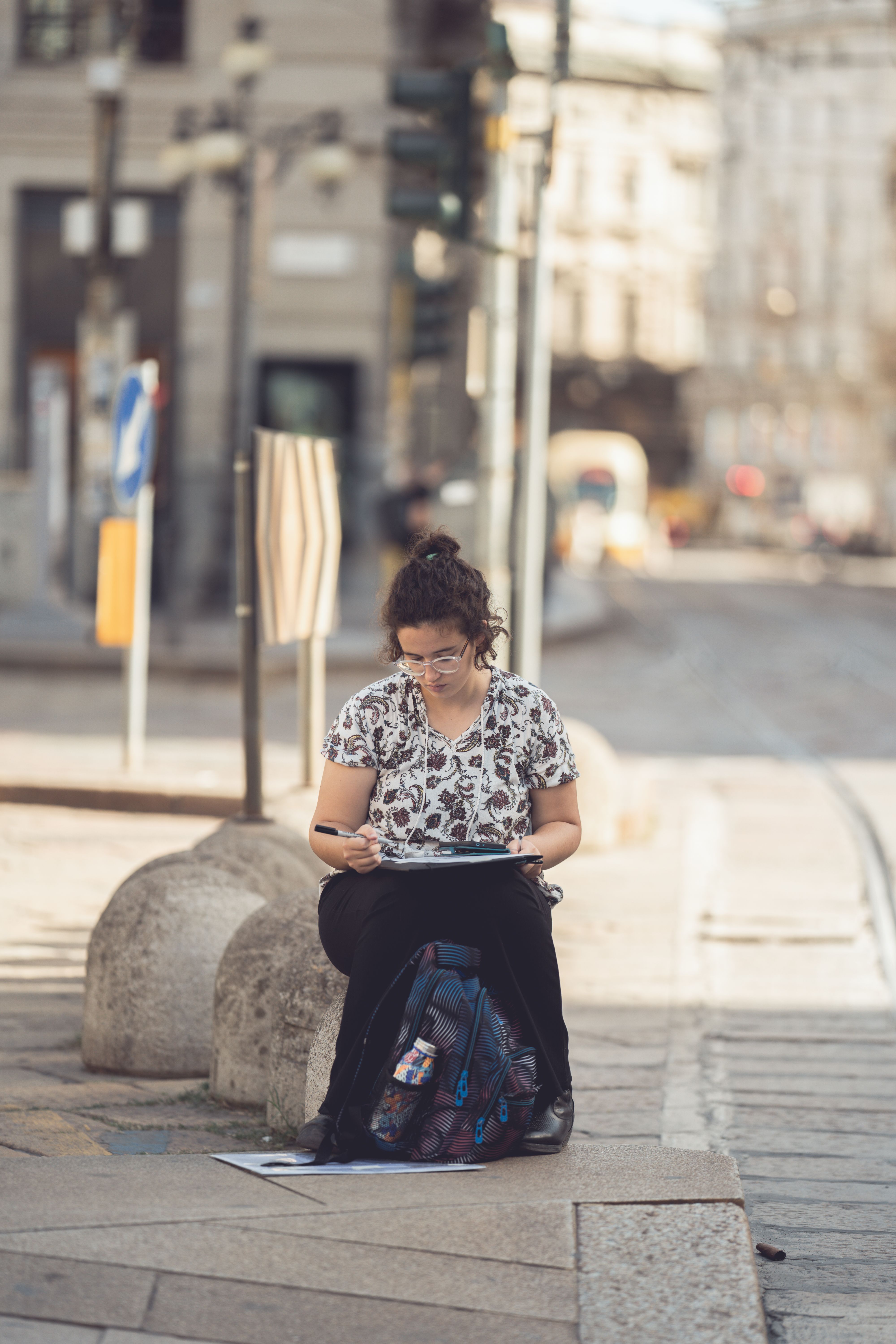 A woman sketching on a city street, capturing urban life in an artistic setting.