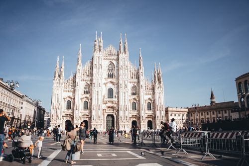 Free Capture of the majestic Milan Cathedral, showcasing its stunning Gothic architecture in a lively city square. Stock Photo