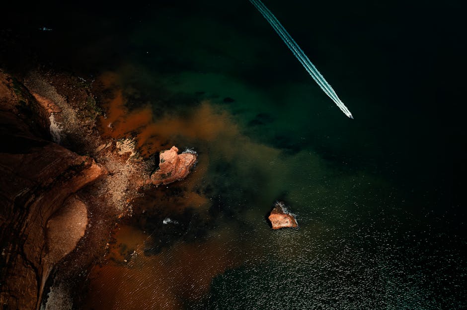 Aerial shot of a speedboat on the sea near the cliffs of Sidmouth, UK, with rich green and brown hue
