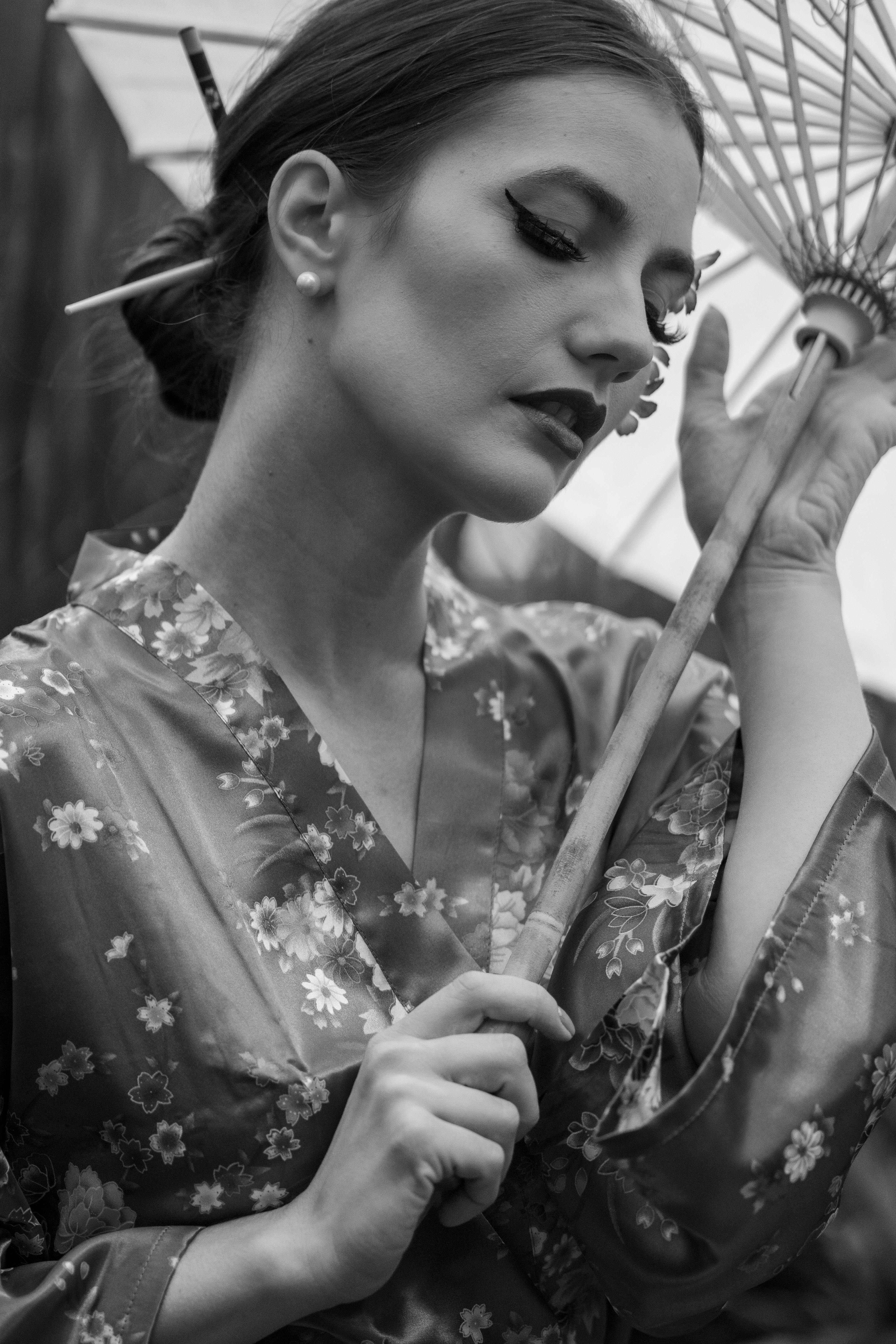 Black and white portrait of a woman in a floral kimono holding a traditional umbrella.