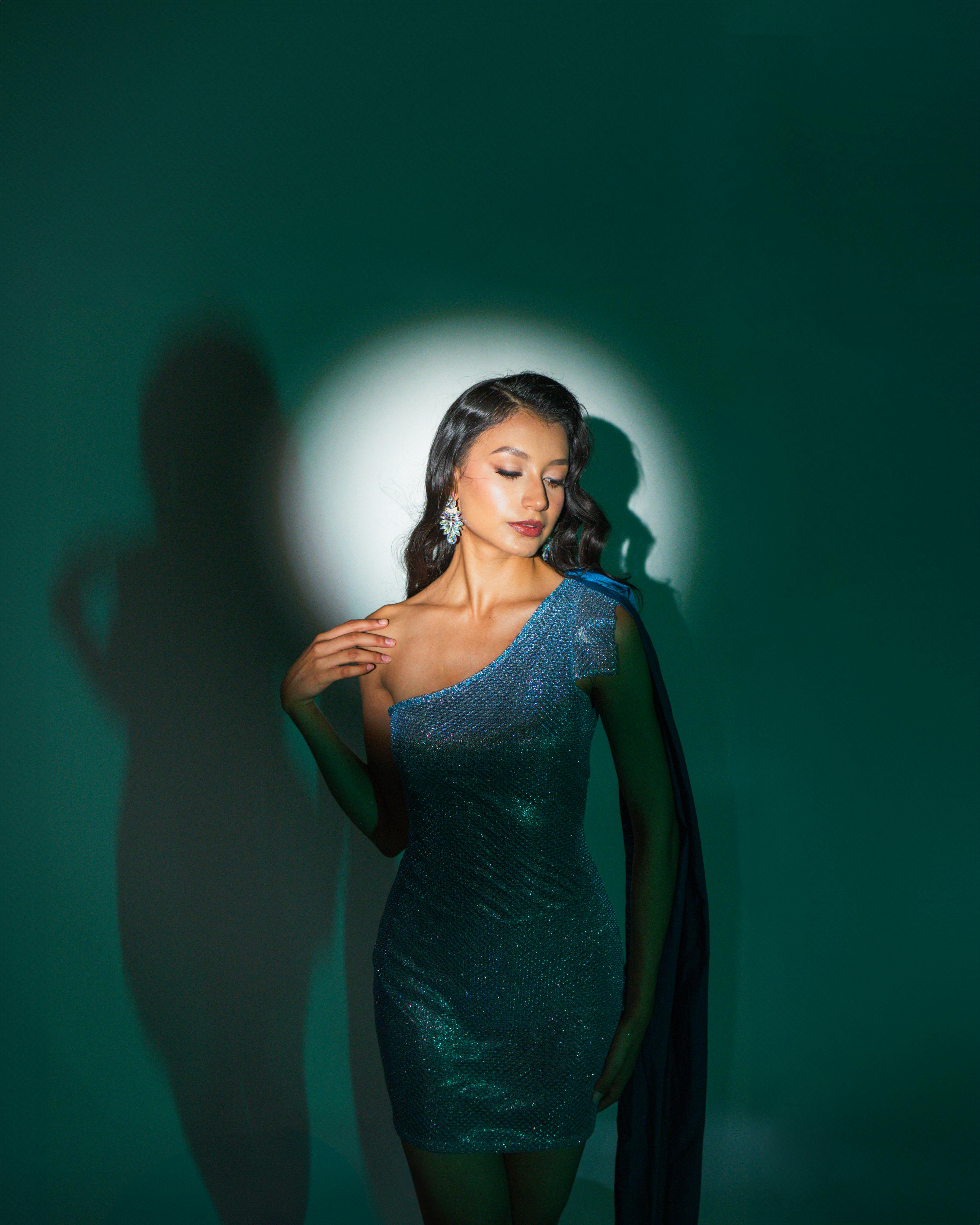 a woman in a blue dress posing in front of a green light