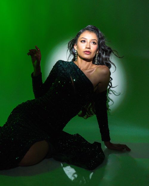Free Graceful portrait of a woman in an elegant green evening gown with dramatic lighting. Stock Photo