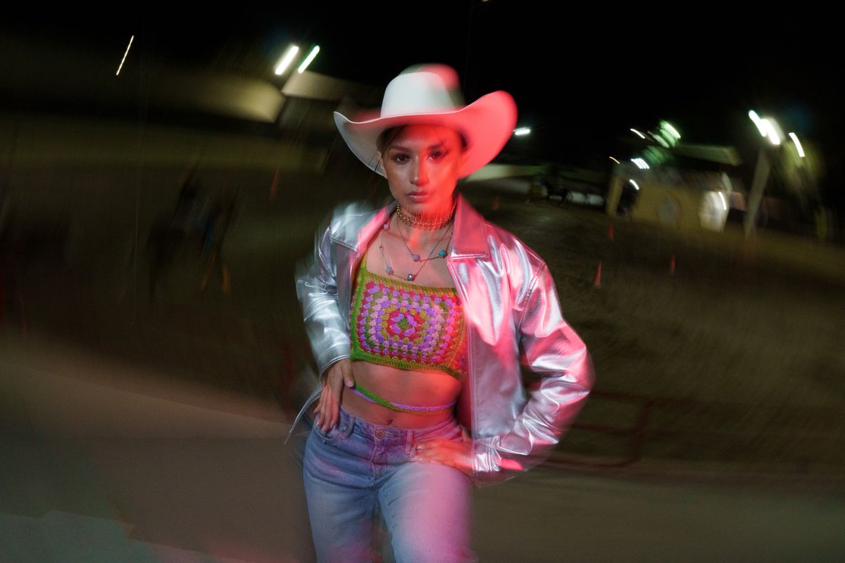Woman in silver jacket and cowboy hat at a festival