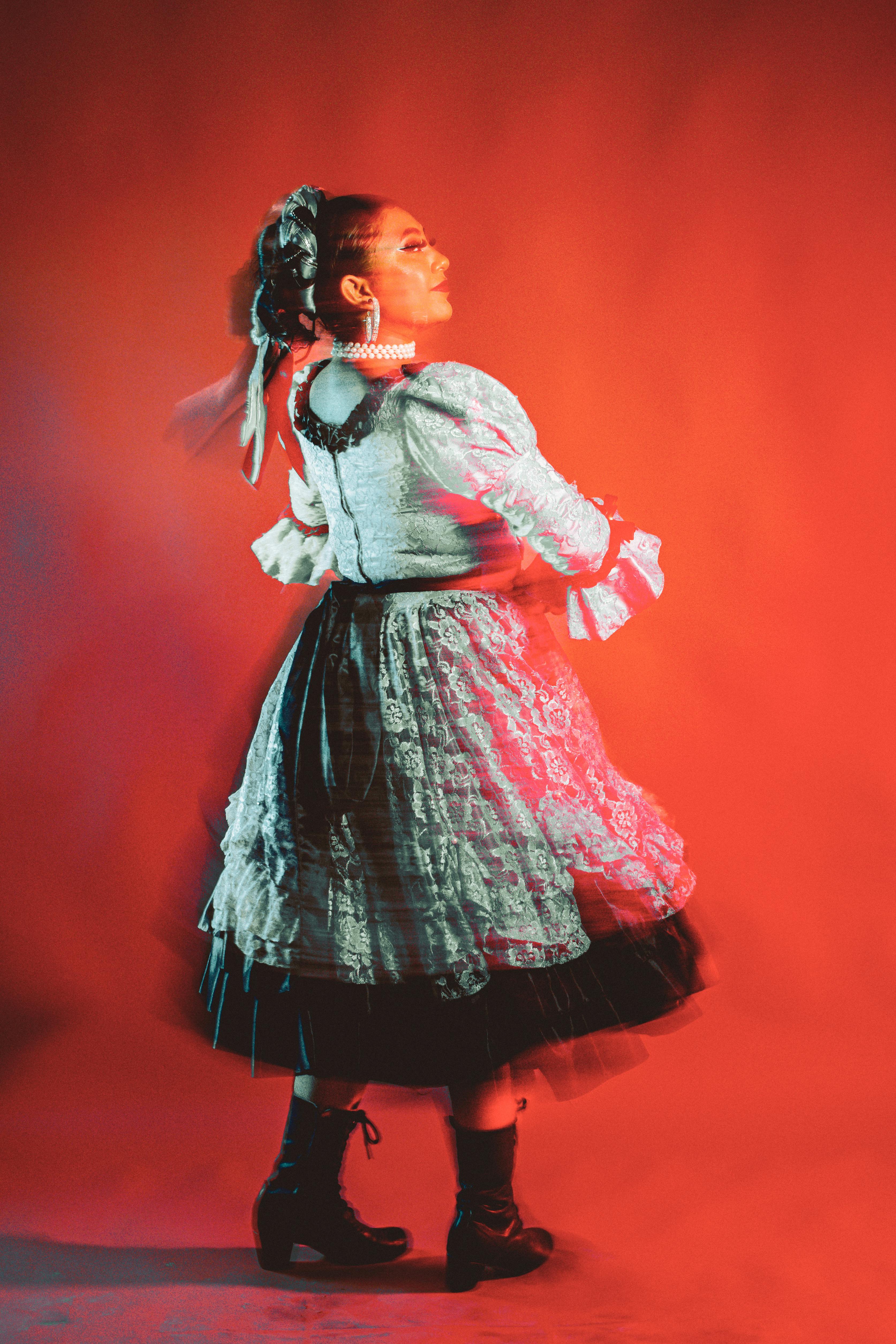 a woman in a dress and skirt is standing in front of a red light