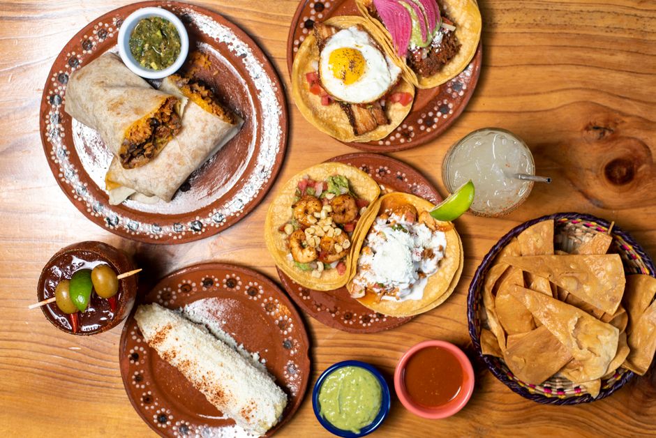 Delicious Mexican dishes including tacos and burritos served on rustic plates with refreshing drinks.