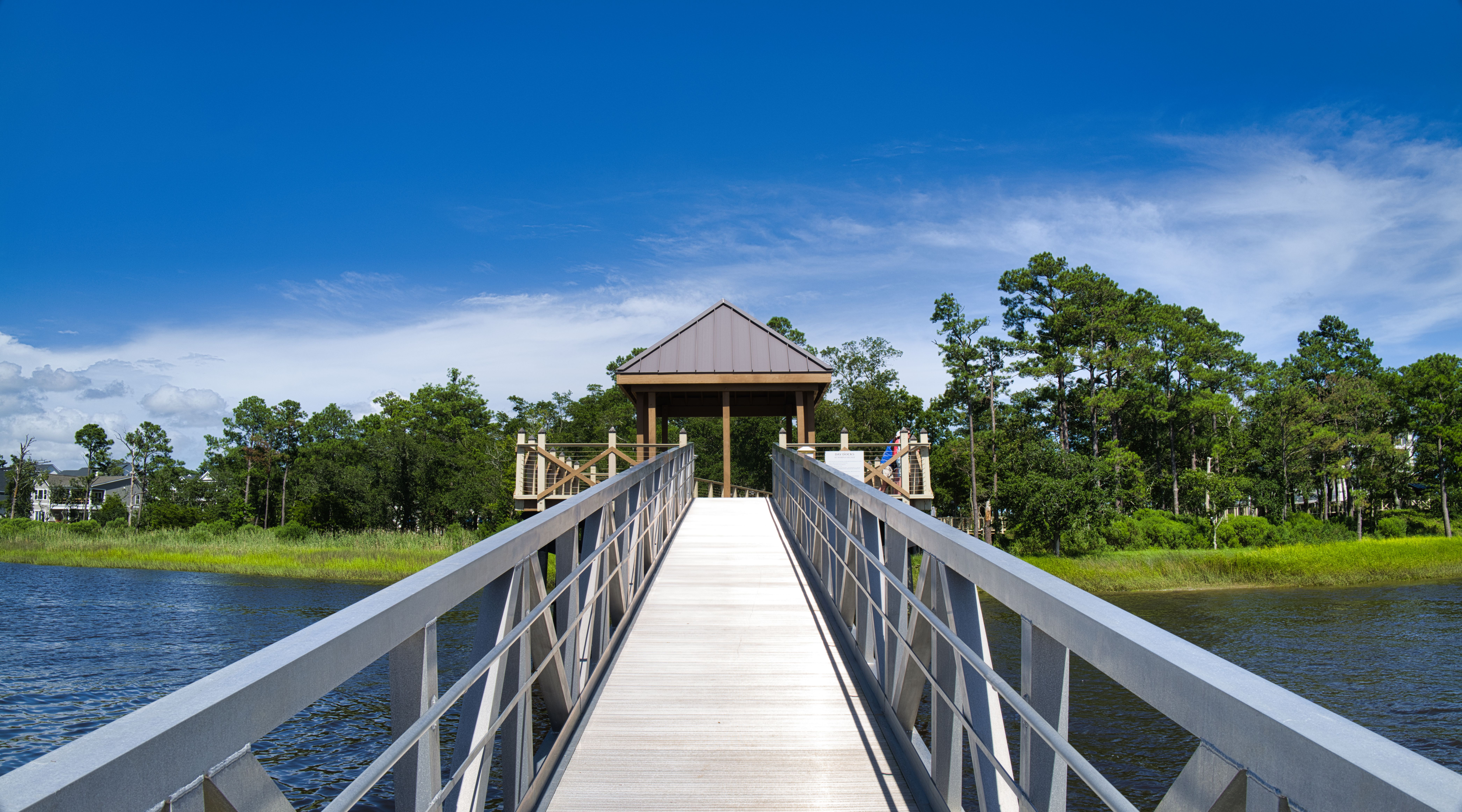 Beautiful wooden boardwalk leading to a gazebo over water in Wilmington, NC with lush greenery.