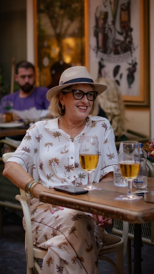 Free A woman enjoying a relaxed moment with drinks at an outdoor restaurant. Stock Photo
