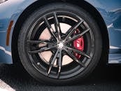The front wheel of a blue car with red brake calipers