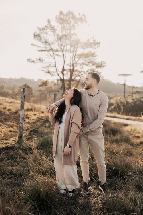 Free A joyful couple standing in a sunlit rural field, enjoying a moment together. Stock Photo