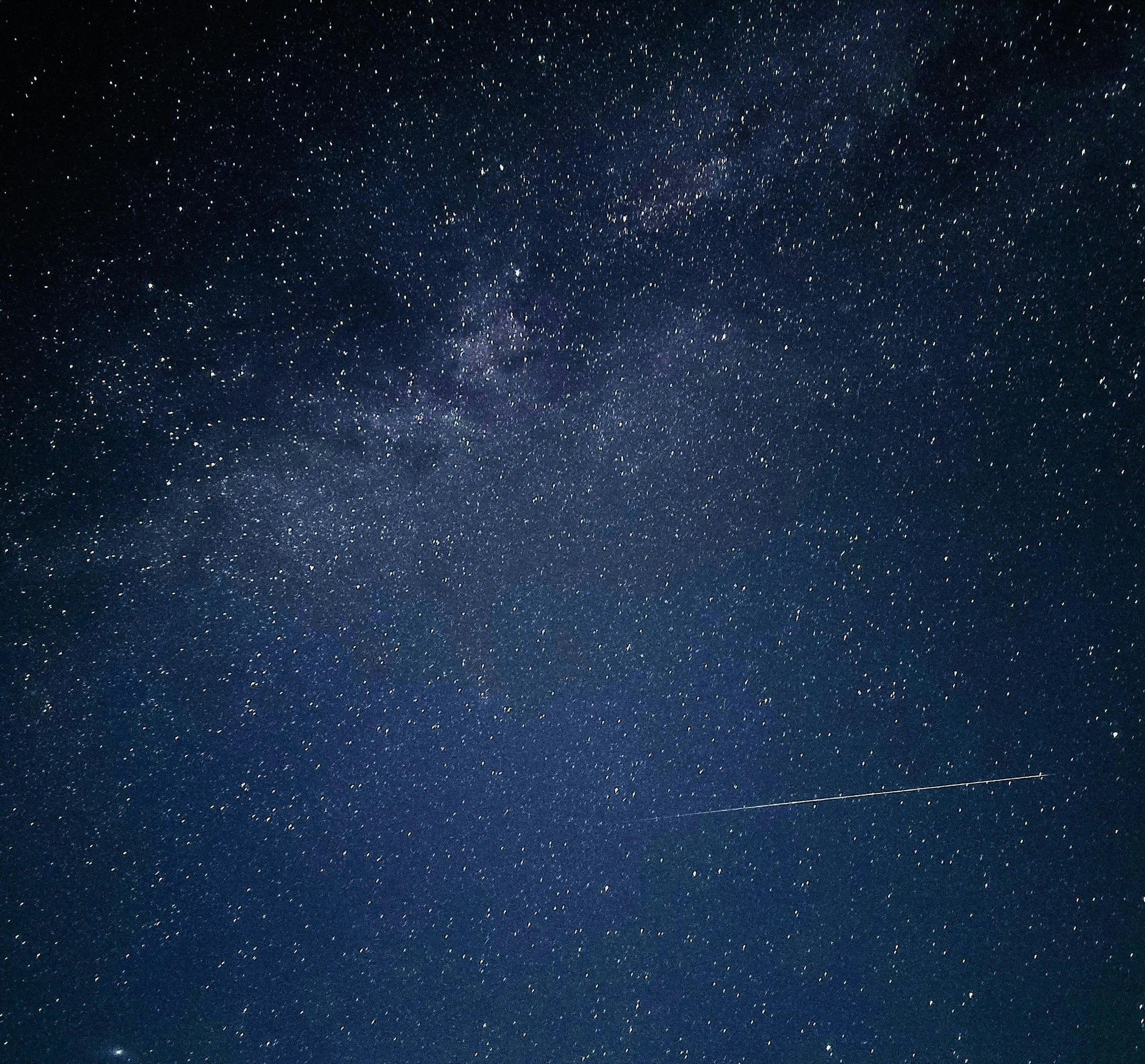 A clear night sky filled with stars and a meteor streaking across.