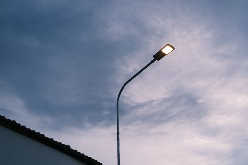 Free An illuminated streetlight stands against a cloudy twilight sky, evoking calm and simplicity. Stock Photo