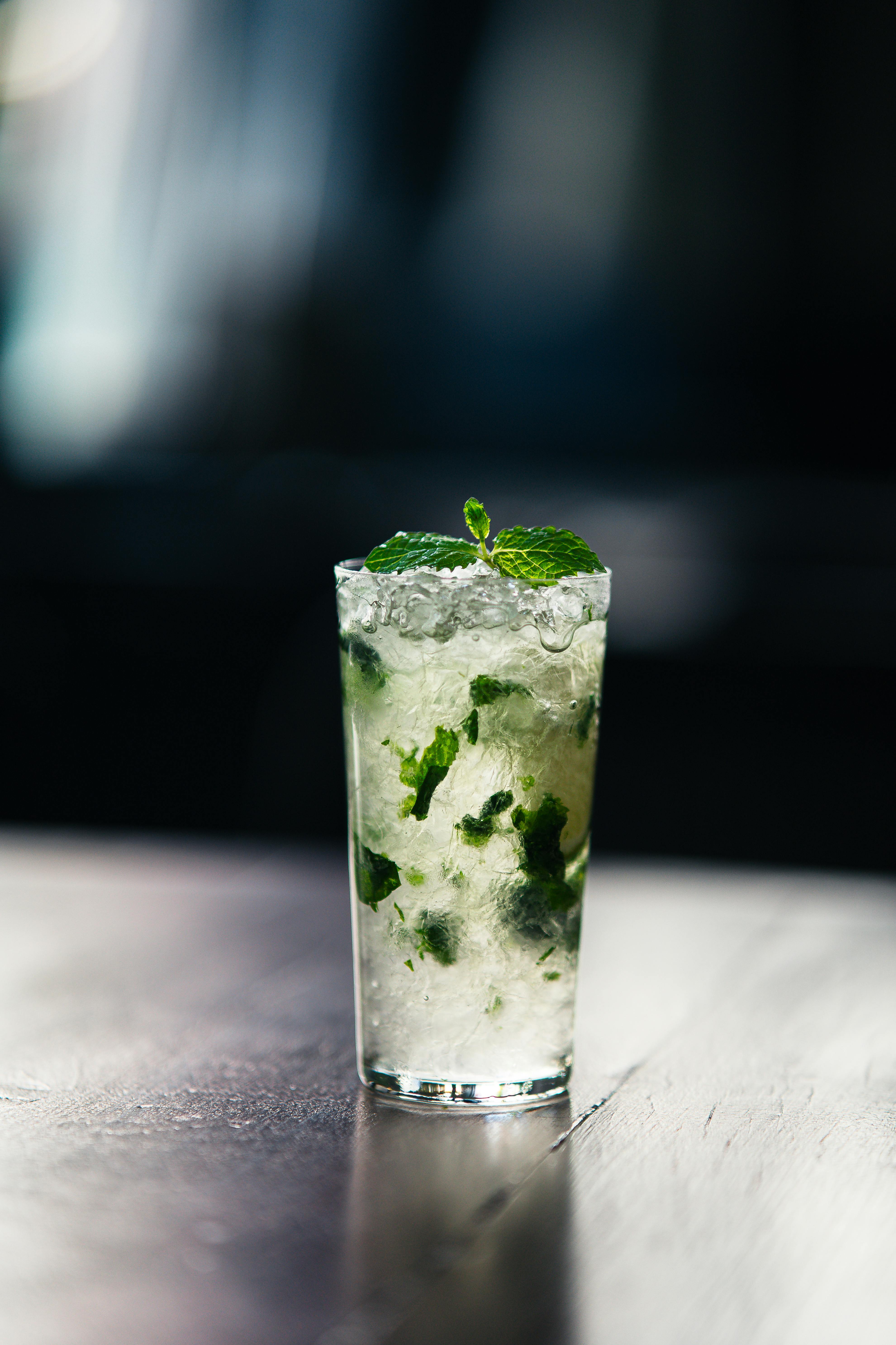 Close-up of a refreshing mojito cocktail with mint leaves on a reflective surface. Perfect for summer vibes.