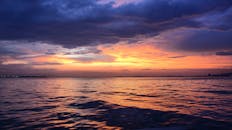 宁静的海洋日落，橙紫交织的绚烂色调倒映在水面上，构成一幅完美的自然风光