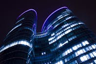 现代摩天大楼的低角度视图，在夜空中点缀着发光的灯光和紫色光影