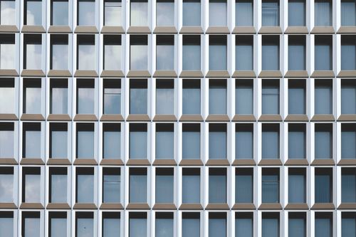Free A striking modern facade showcasing a pattern of repetitive glass windows under daylight. Stock Photo