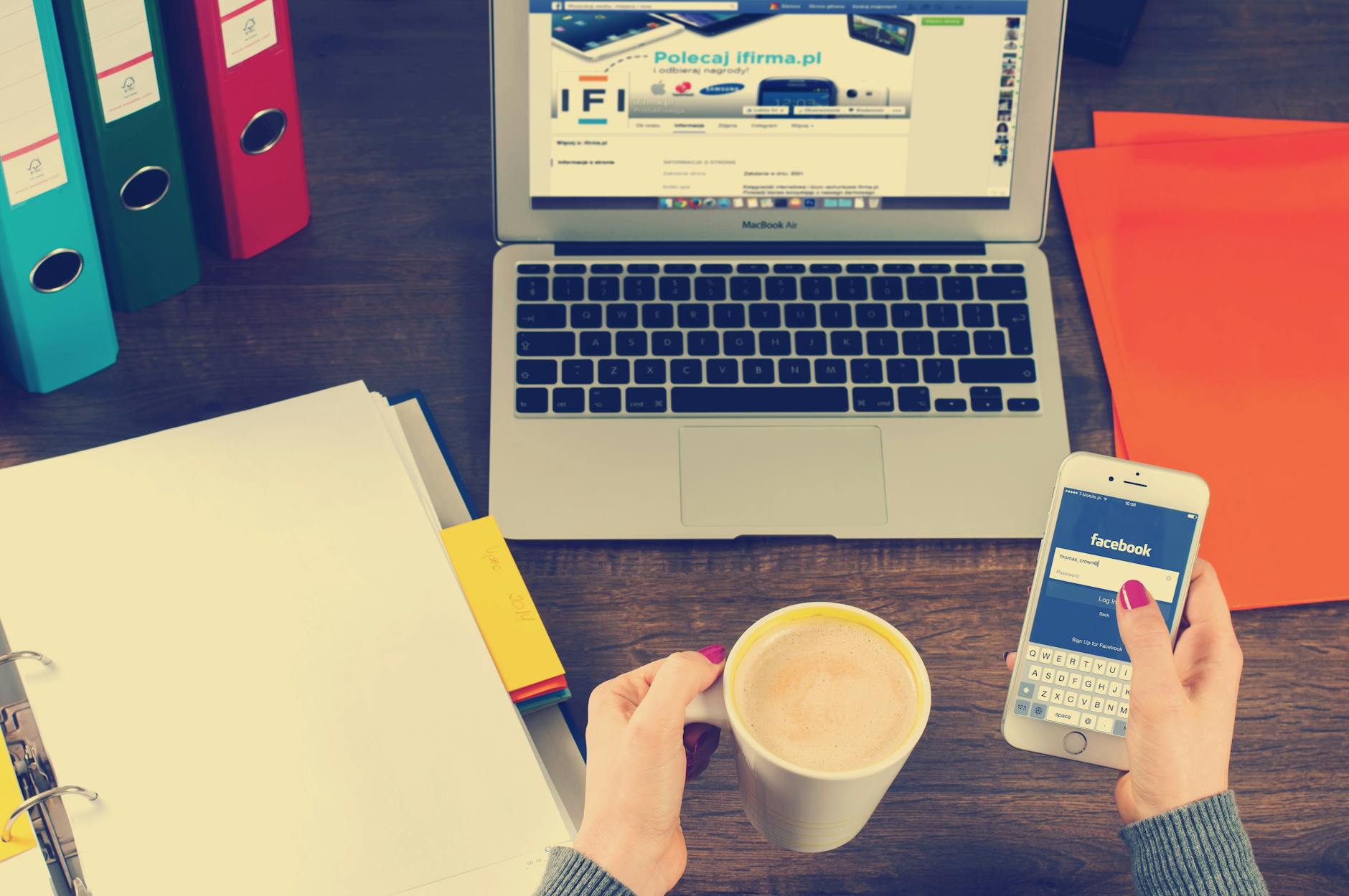 Man Holding Mug Filled With Coffee in Front of Macbook Air on Table