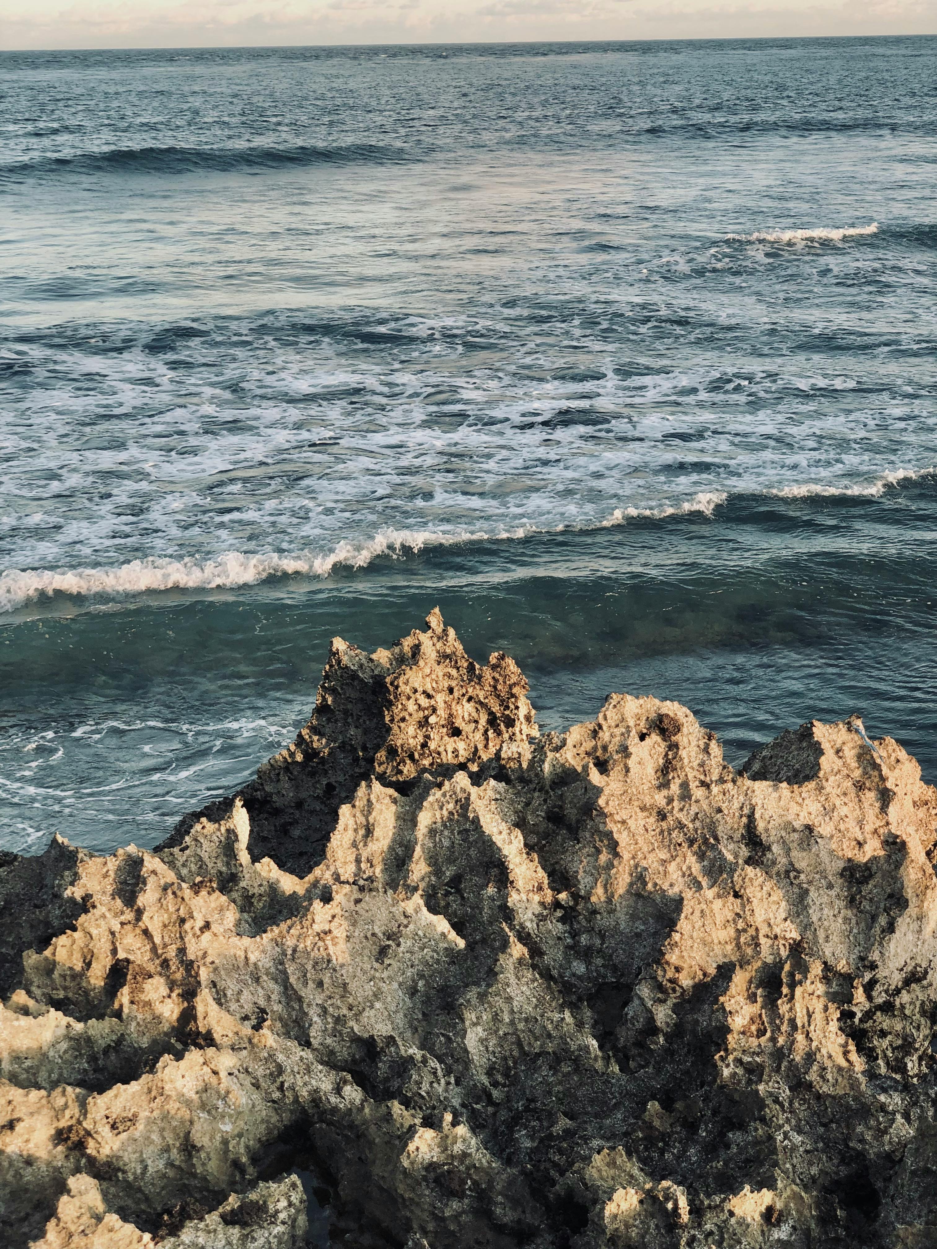 Rugged coastline with dramatic rock formations by the ocean waves at sunset.