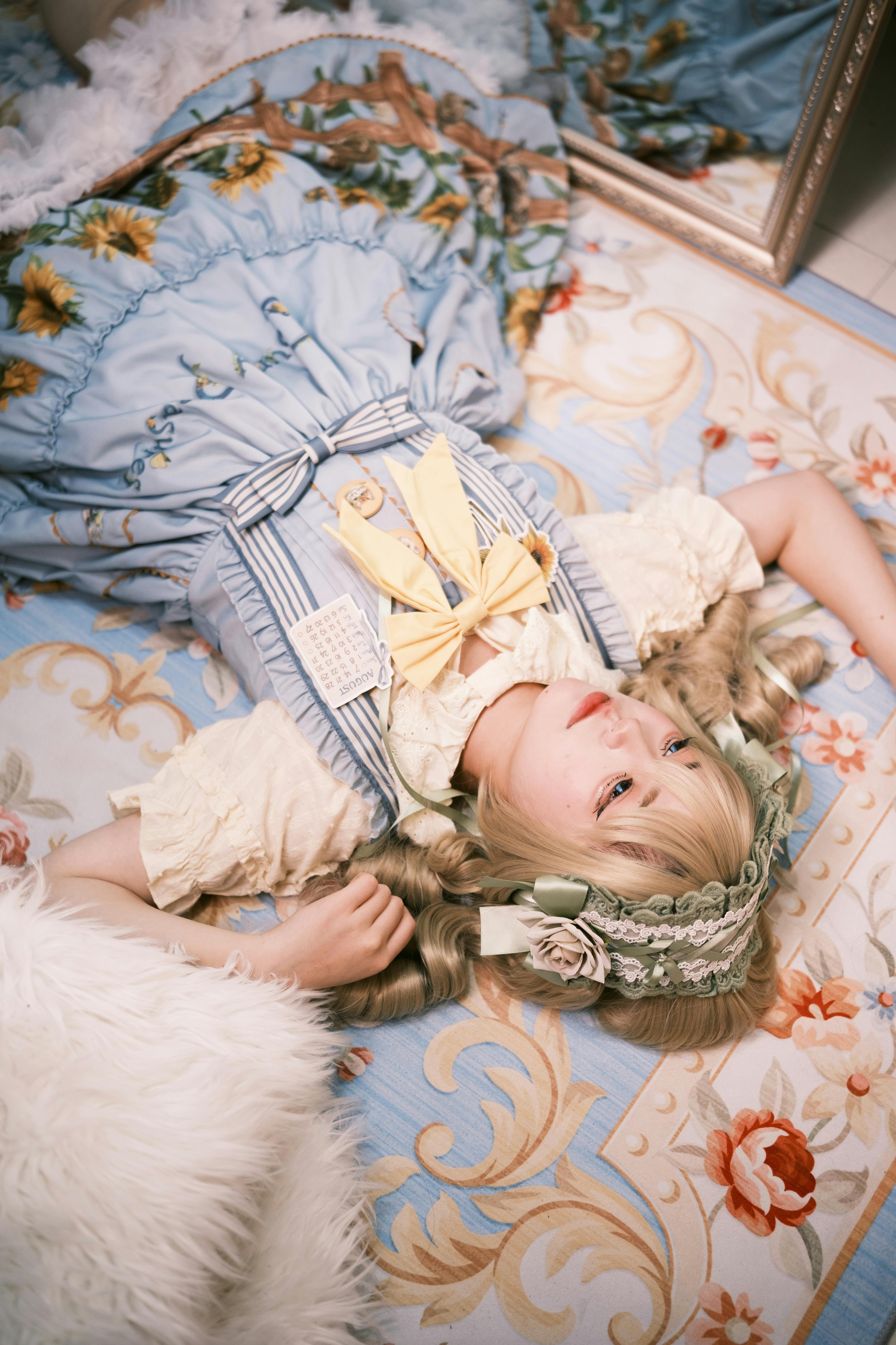 teenage girl in victorian style dress and headdress lying on back