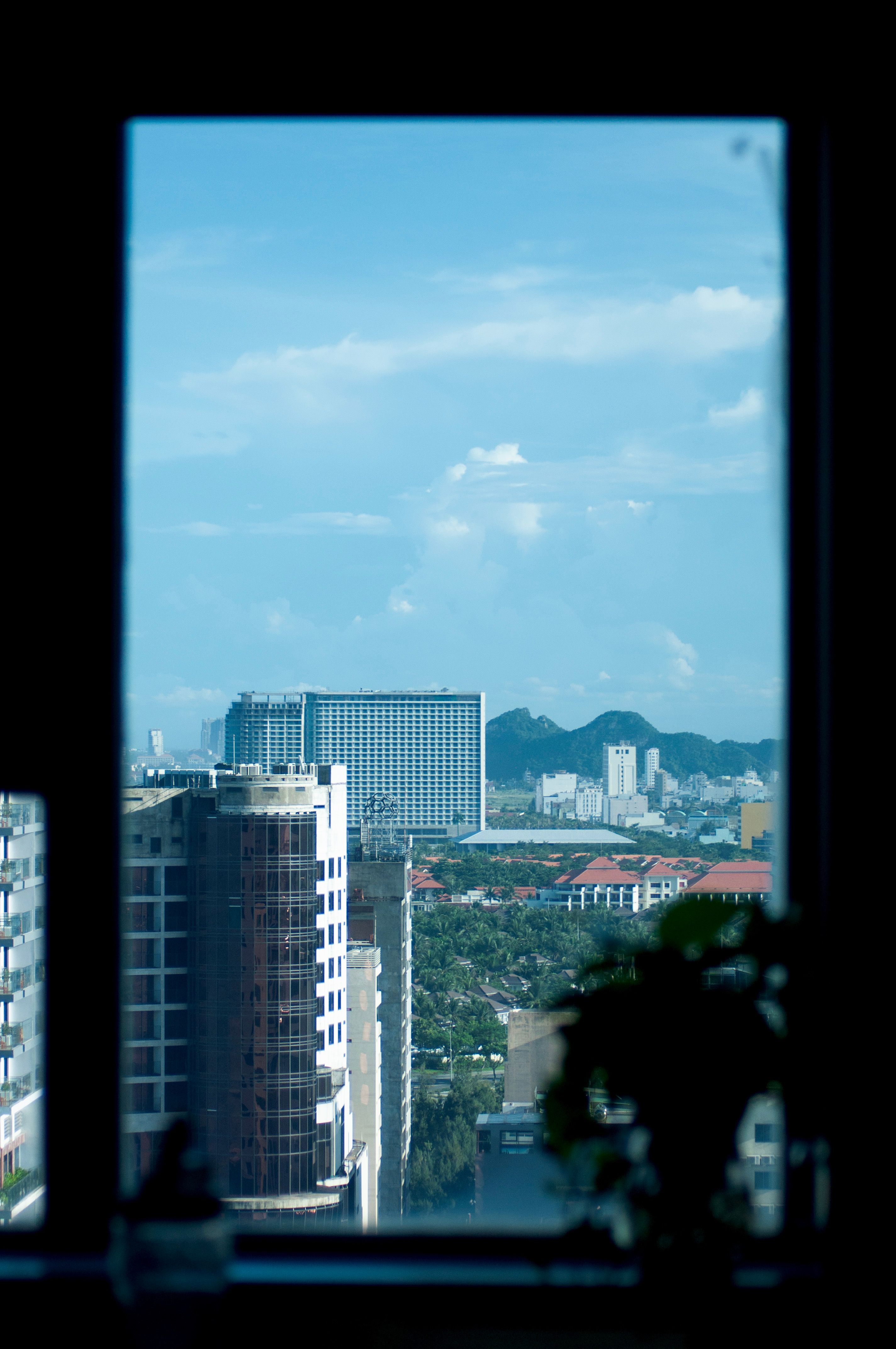 Explore the vibrant skyline of Da Nang, Vietnam through a window frame, capturing modern architecture.