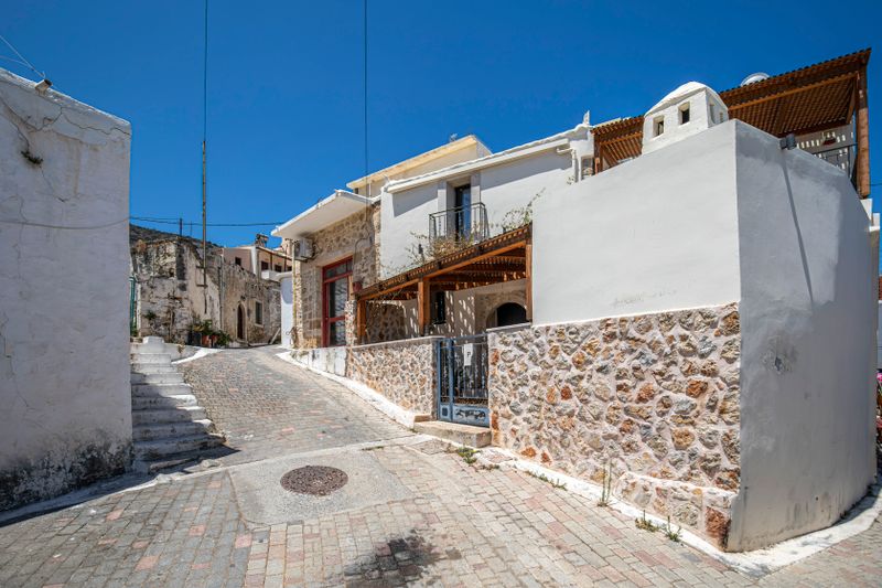 Narrow cobbled lane with stone walls and steps in a traditional Cretan village