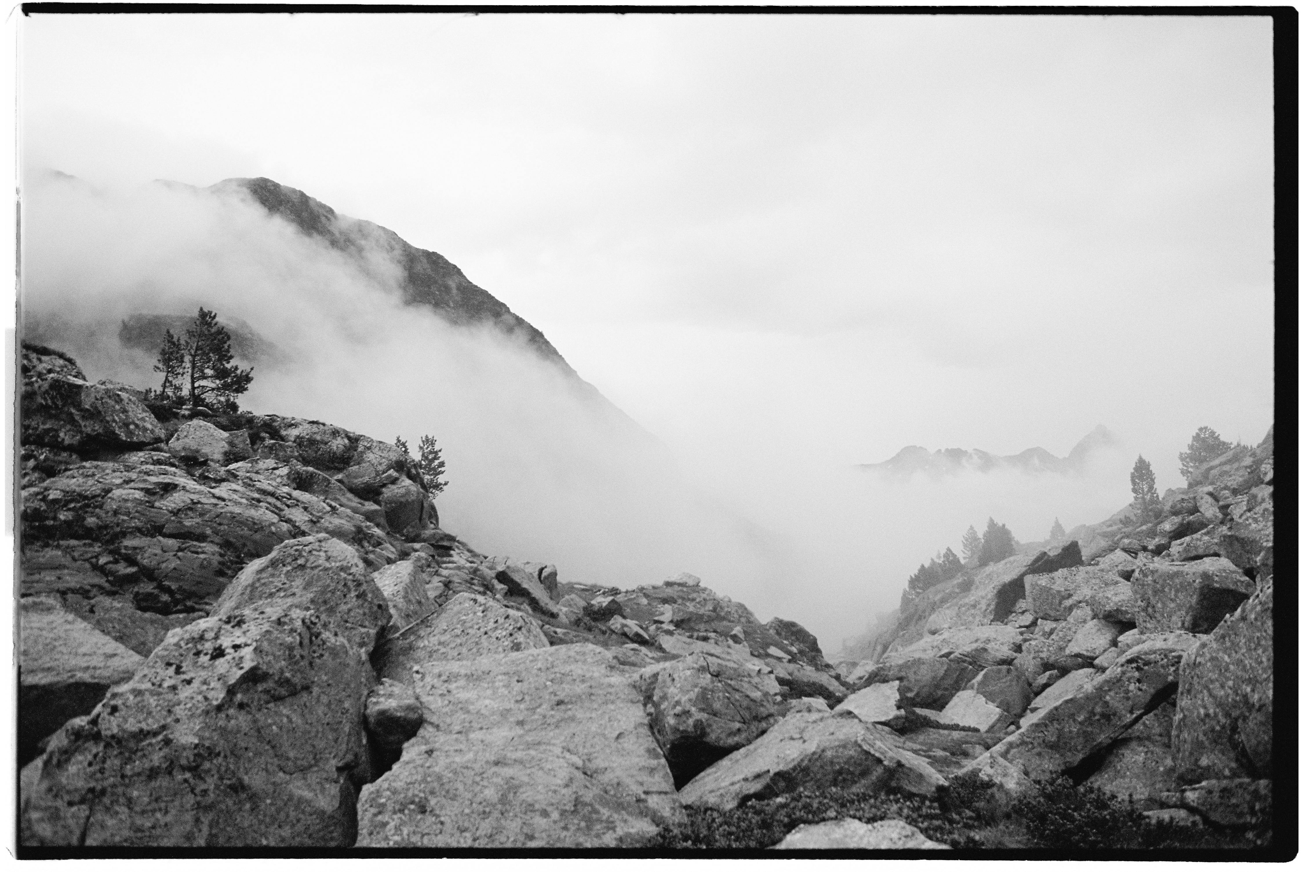 Black and white landscape featuring foggy mountains and rocky terrain.