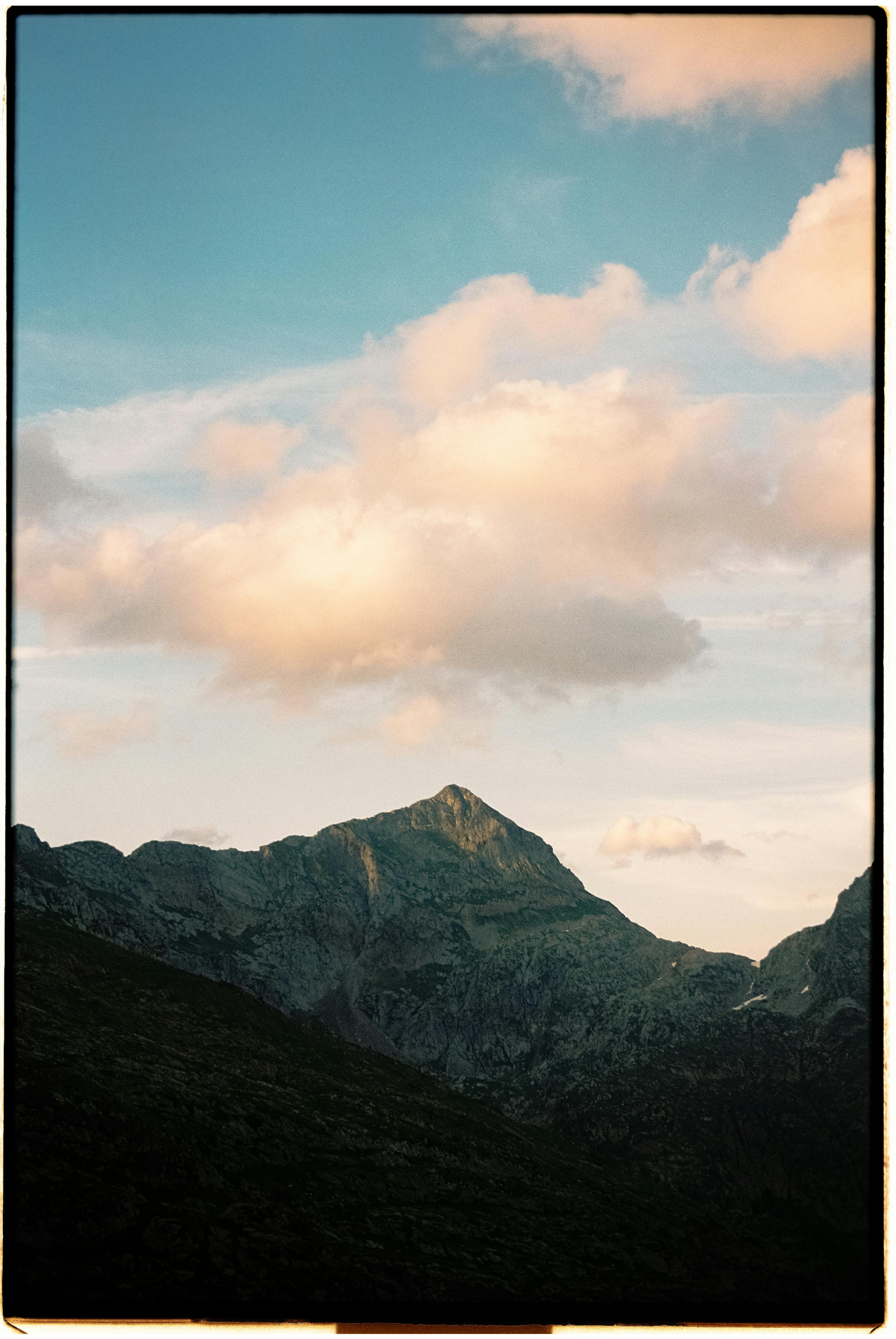 A scenic view of a mountain peak beneath soft clouds, suitable for travel and nature themes.