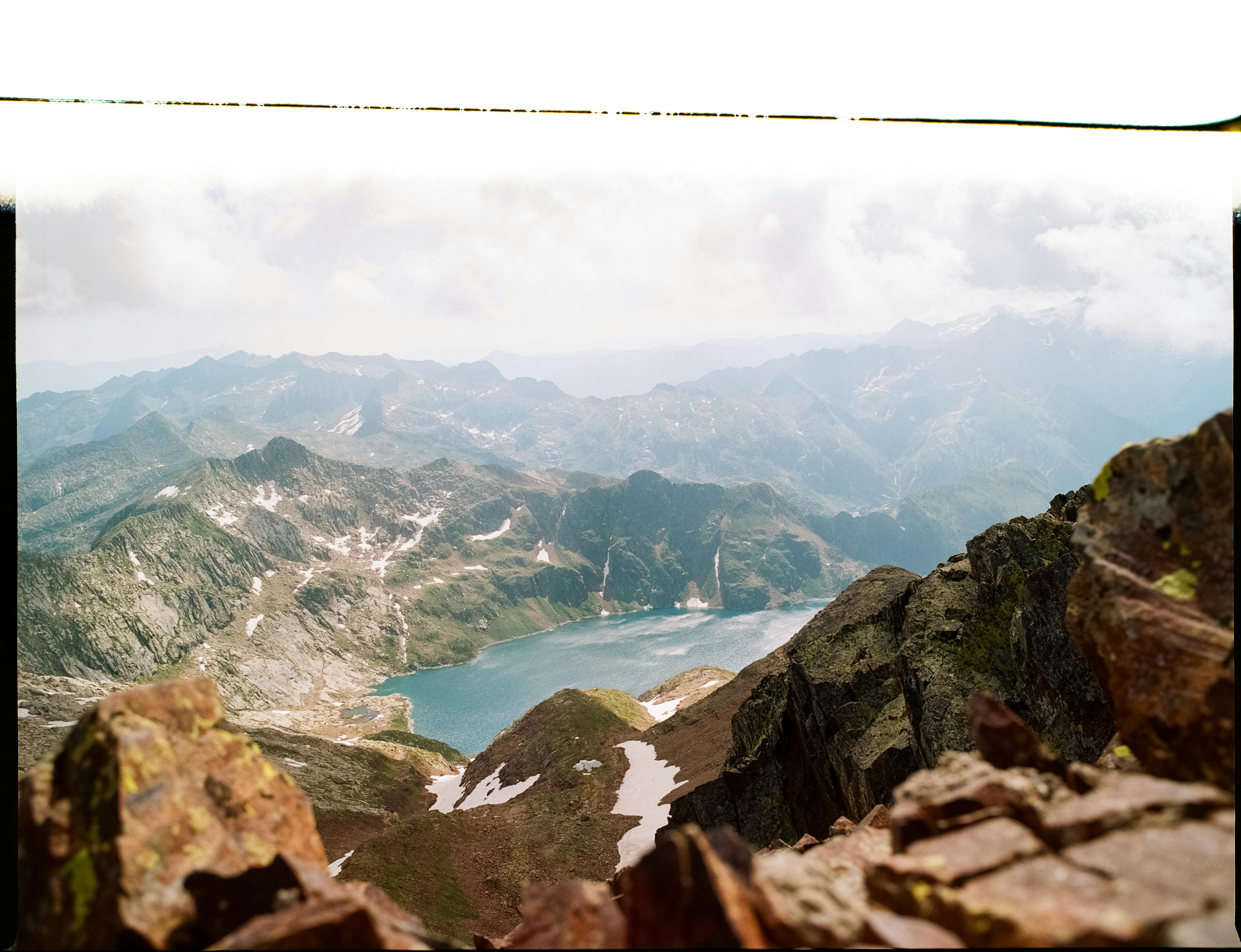 Stunning panoramic view of a mountain lake surrounded by rocky peaks and snow patches.