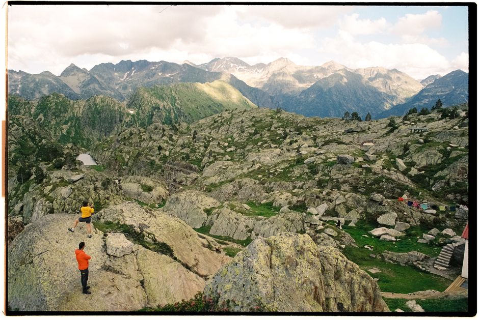 Dramatic view of hikers in a rugged, mountainous terrain under a summer sky.