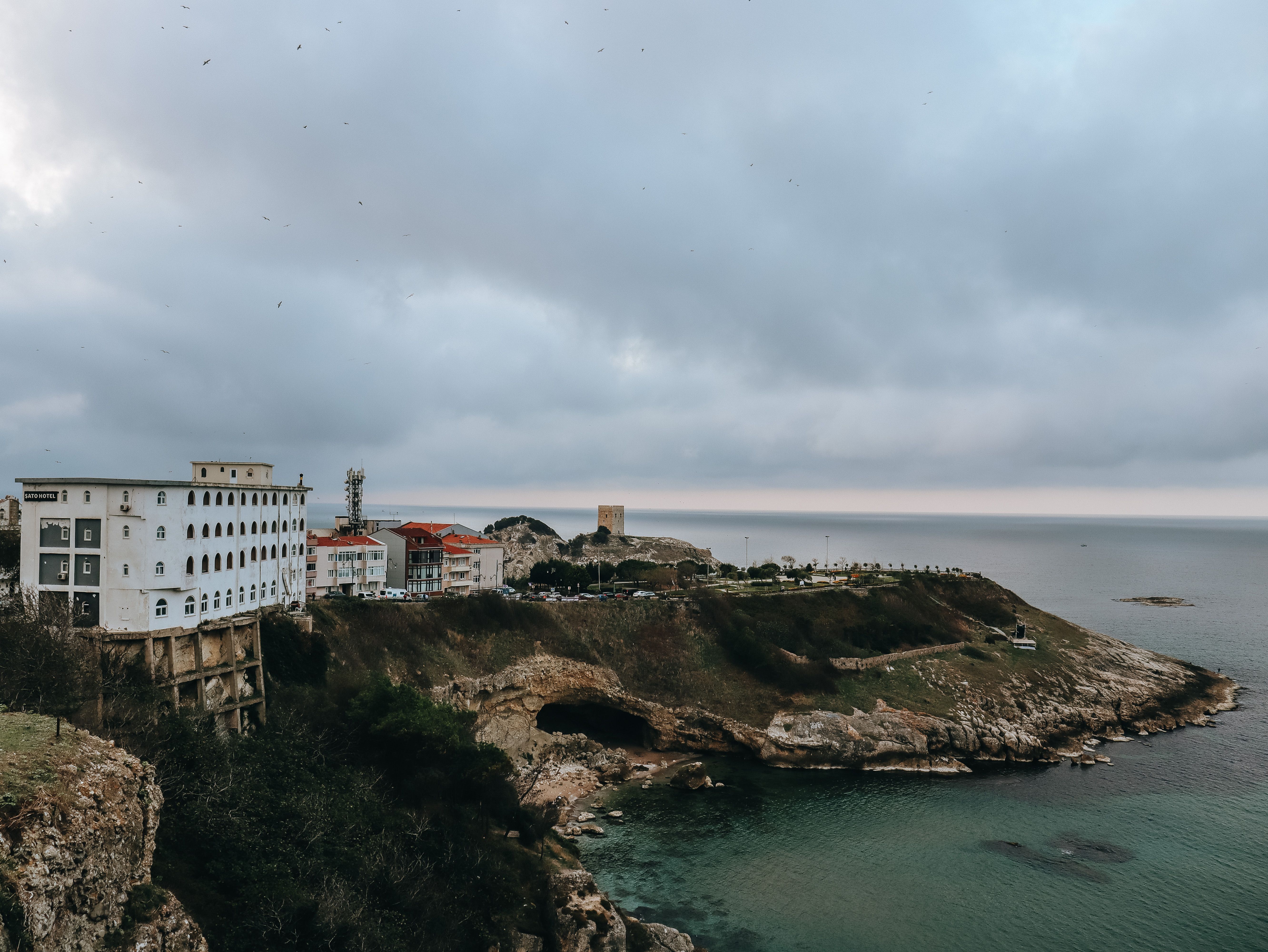 dramatic cliffside citadel overlooking a river town with colorful buildings