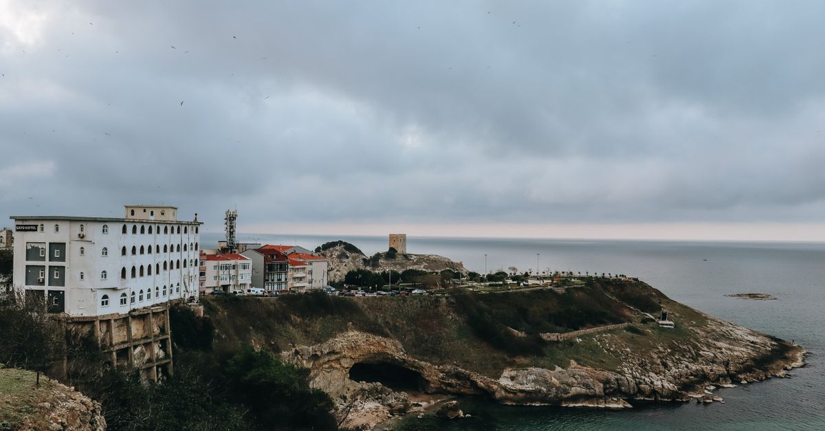 dramatic cliffside citadel overlooking a river town with colorful buildings