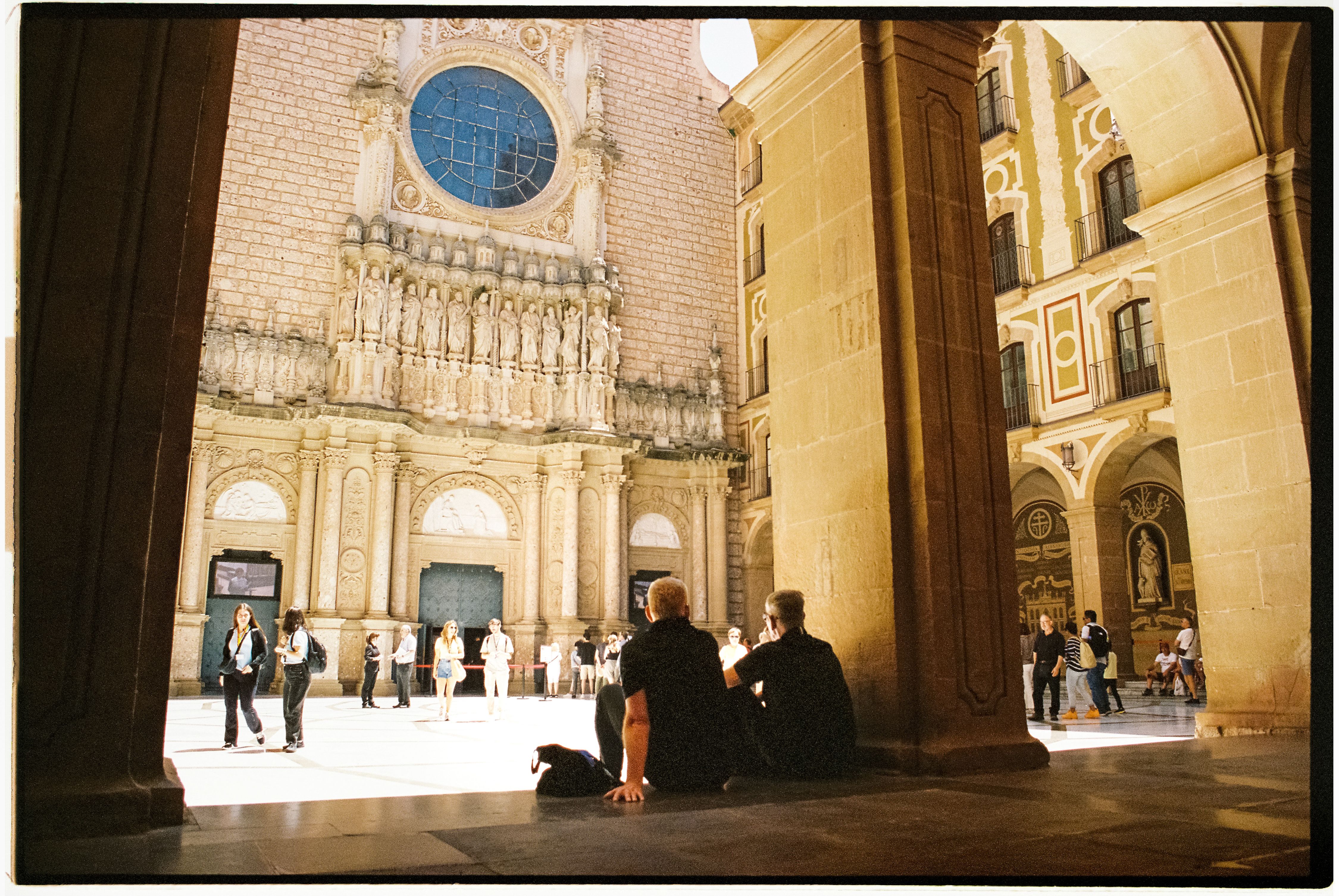 Tourists explore the grand historic church courtyard with intricate architecture and sculptures.