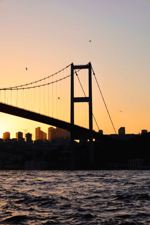 Free A stunning silhouette of Bosphorus Bridge at sunset with water and city skyline, Istanbul. Stock Photo