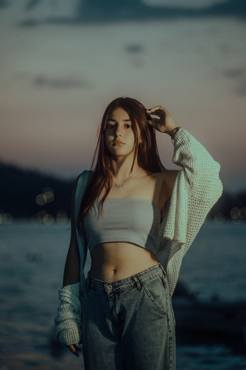 Free Fashionable woman posing at sunset by the ocean, blending style and nature. Stock Photo