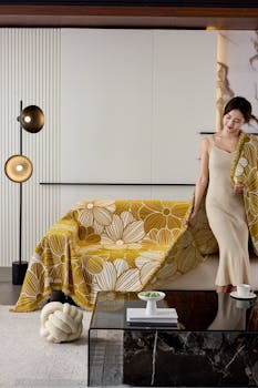Stylish woman in a modern living room with a floral blanket, creating a cozy atmosphere.