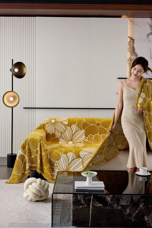 Free Stylish woman in a modern living room with a floral blanket, creating a cozy atmosphere. Stock Photo