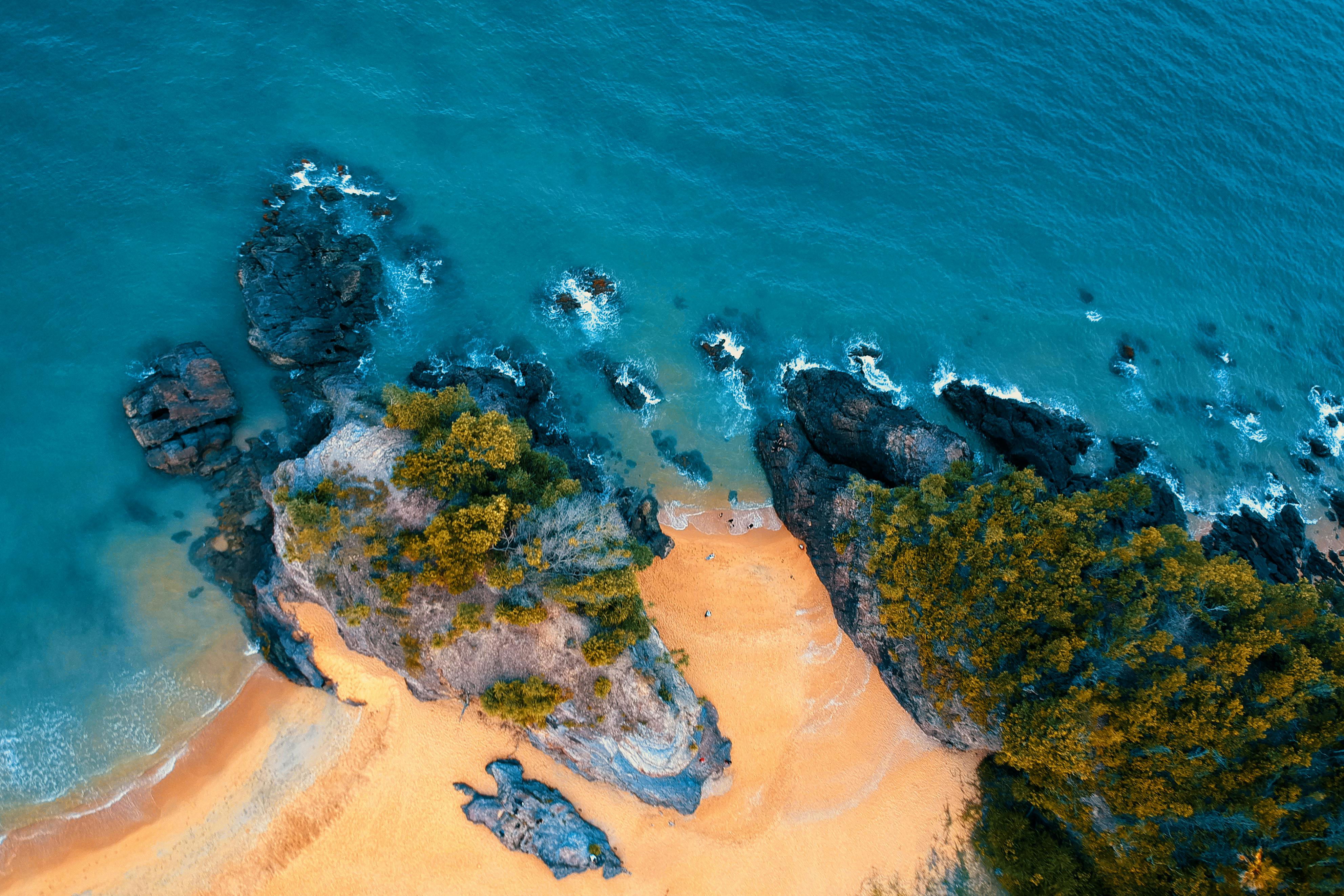 空中拍摄的沙滩绿松石水域被岩石悬崖环绕，景象令人惊叹