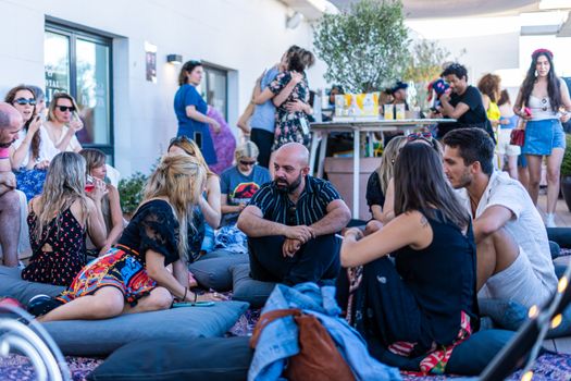 Adults socializing and relaxing at a stylish rooftop lounge party during the day.