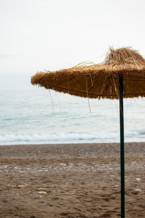Free A tranquil beach with a thatched umbrella, showcasing Ténès, Algeria's coastal beauty. Stock Photo
