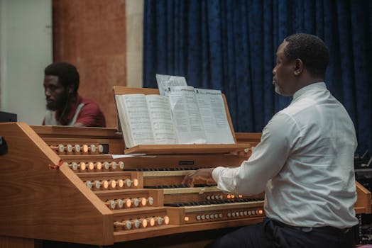 Two African musicians playing a classical pipe organ indoors, showcasing talent and focus.